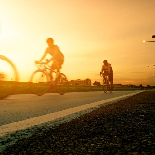 Blur photo sports man ride bicycles with speed motion on the road in the evening with sunset sky. Summer outdoor exercise for healthy and happy life. Cyclist riding mountain bike on bike lane. Team.